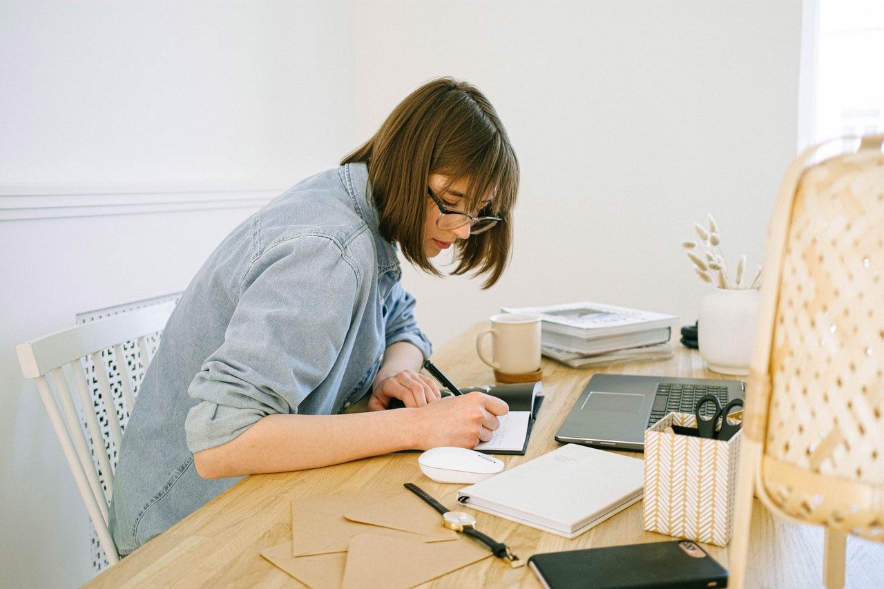 mujer sentada en un escritorio escribiendo en un diario