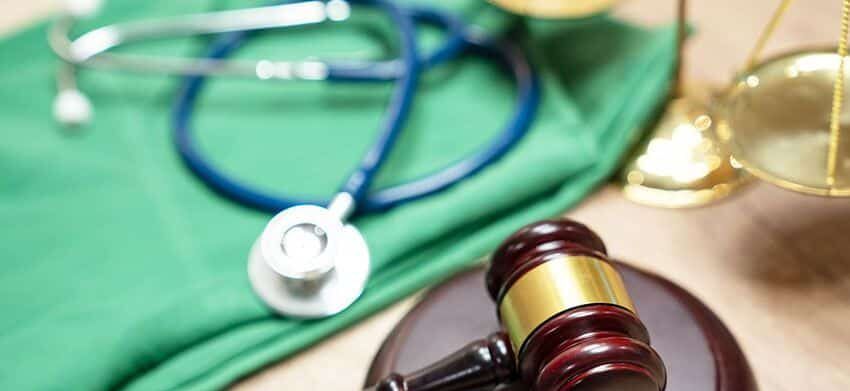 gavel on top of a table next to a pair of scrubs and stethoscope