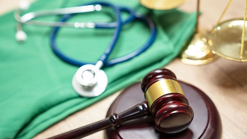 gavel on top of a table next to a pair of scrubs and stethoscope