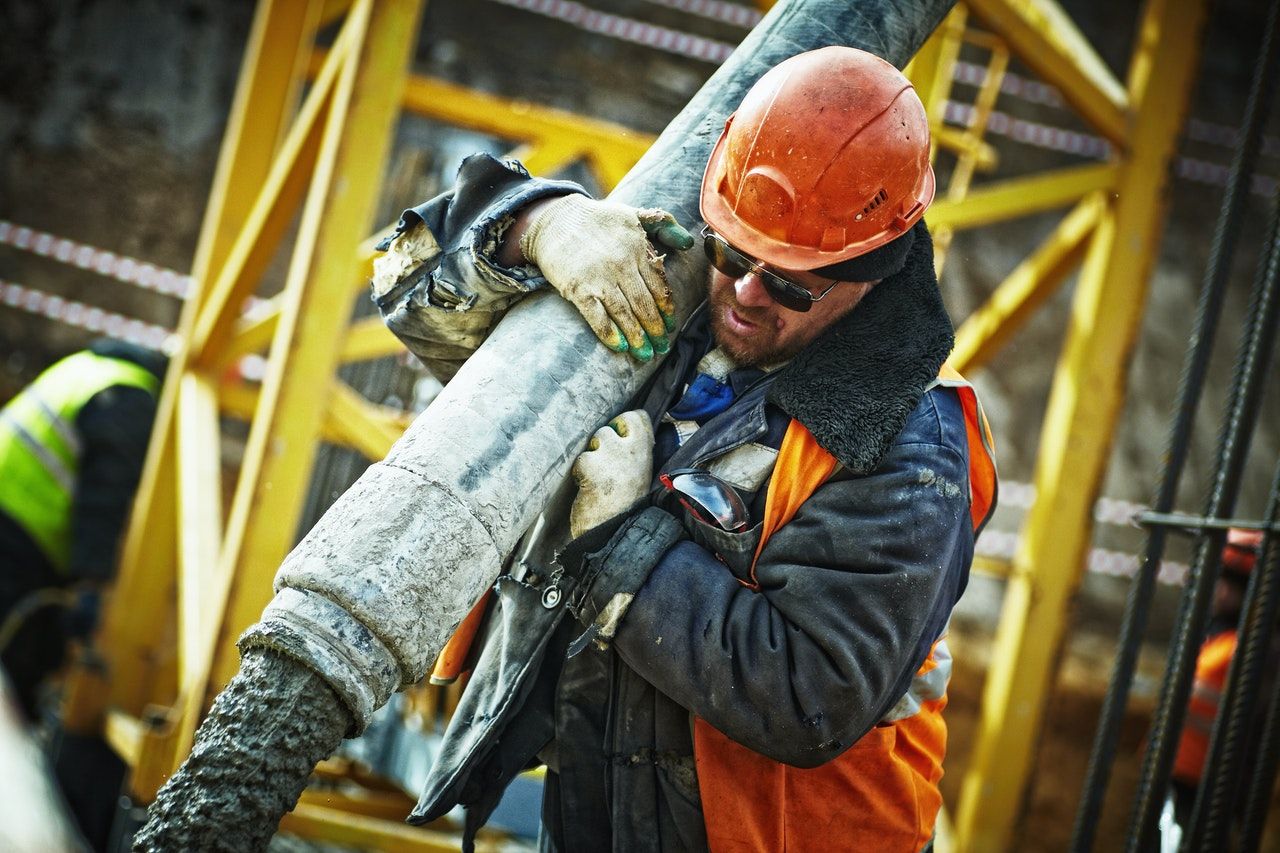 construction worker holding up pipe on his shoulder